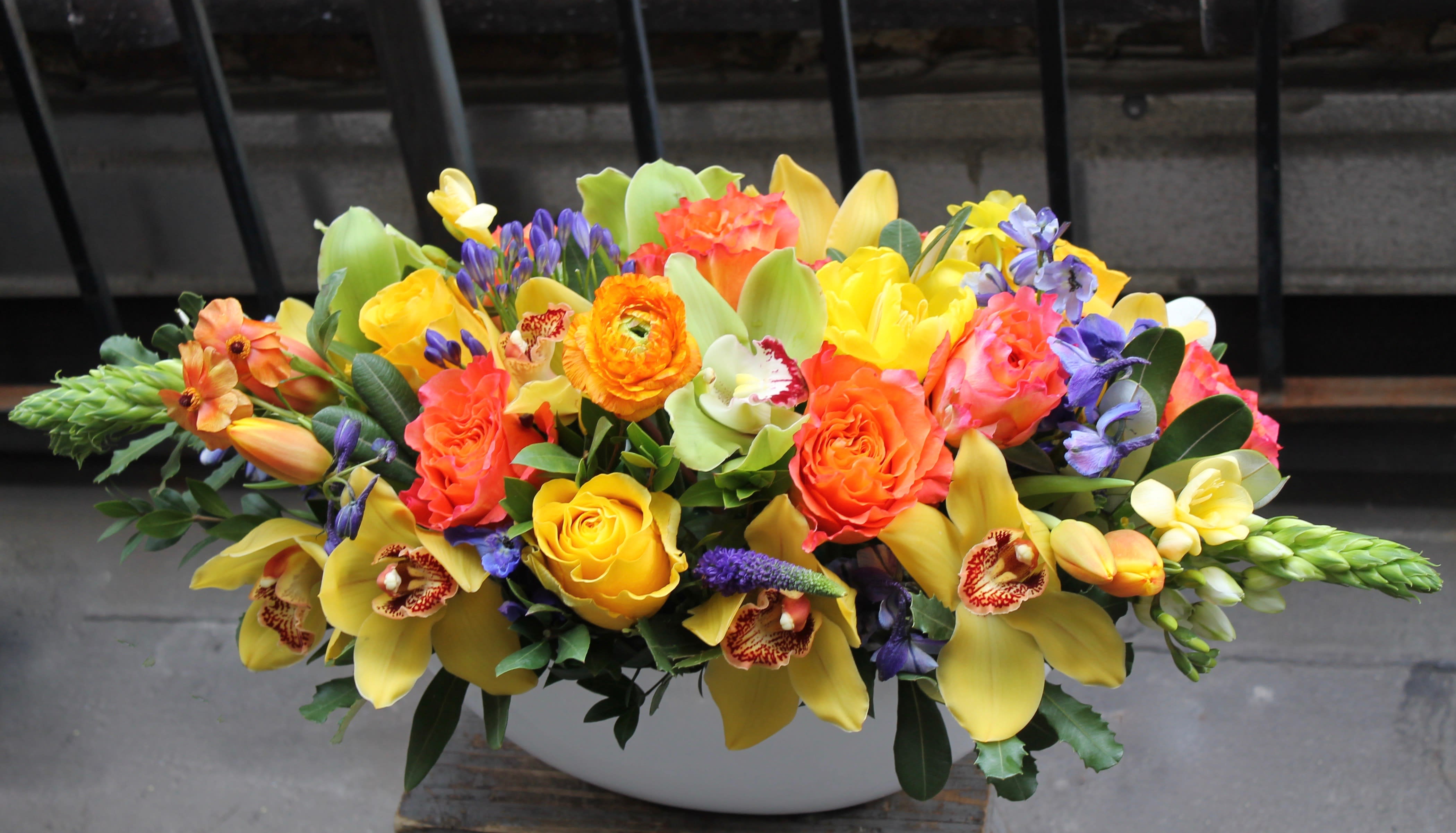 Color Pop - Long rectangular vase filled with colorful seasonal flowers.  Perfect for table or centerpiece. Pictured are tulips, roses, lilies, hyacinth and hydrangeas. 