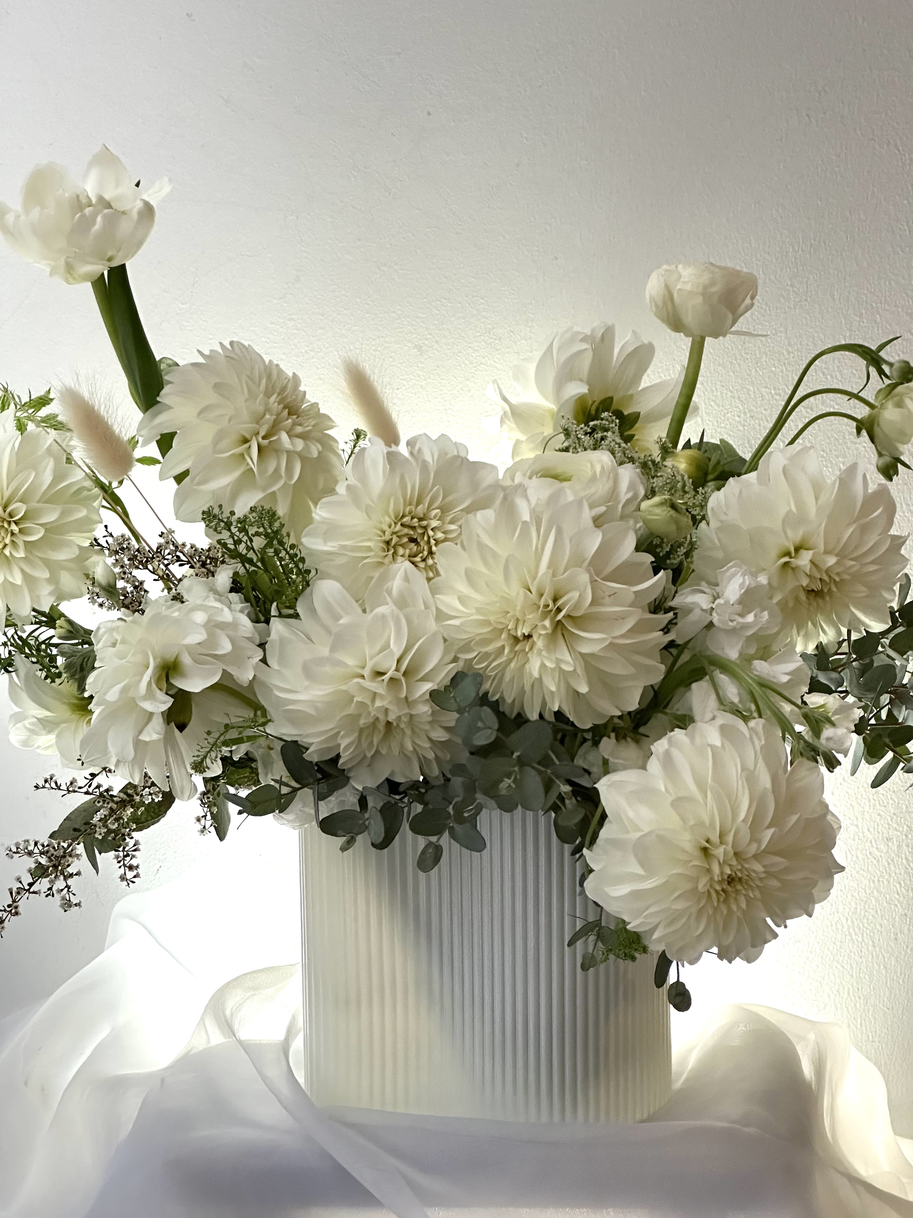 Diamond - Seasonal white flowers in clear vase. Pictured are roses, peony. orchids, ranunculus, calla lily, stock and spray roses with dusty miller leaves. Very lush arrangement with a wow factor. Send the best flowers from the best florist in nyc.