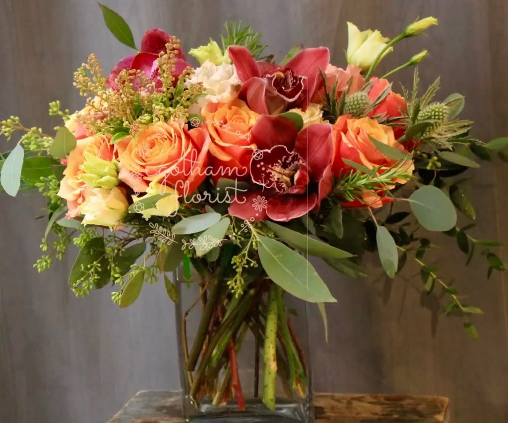 Mixed bouquet of orange and red flowers in a clear glass vase