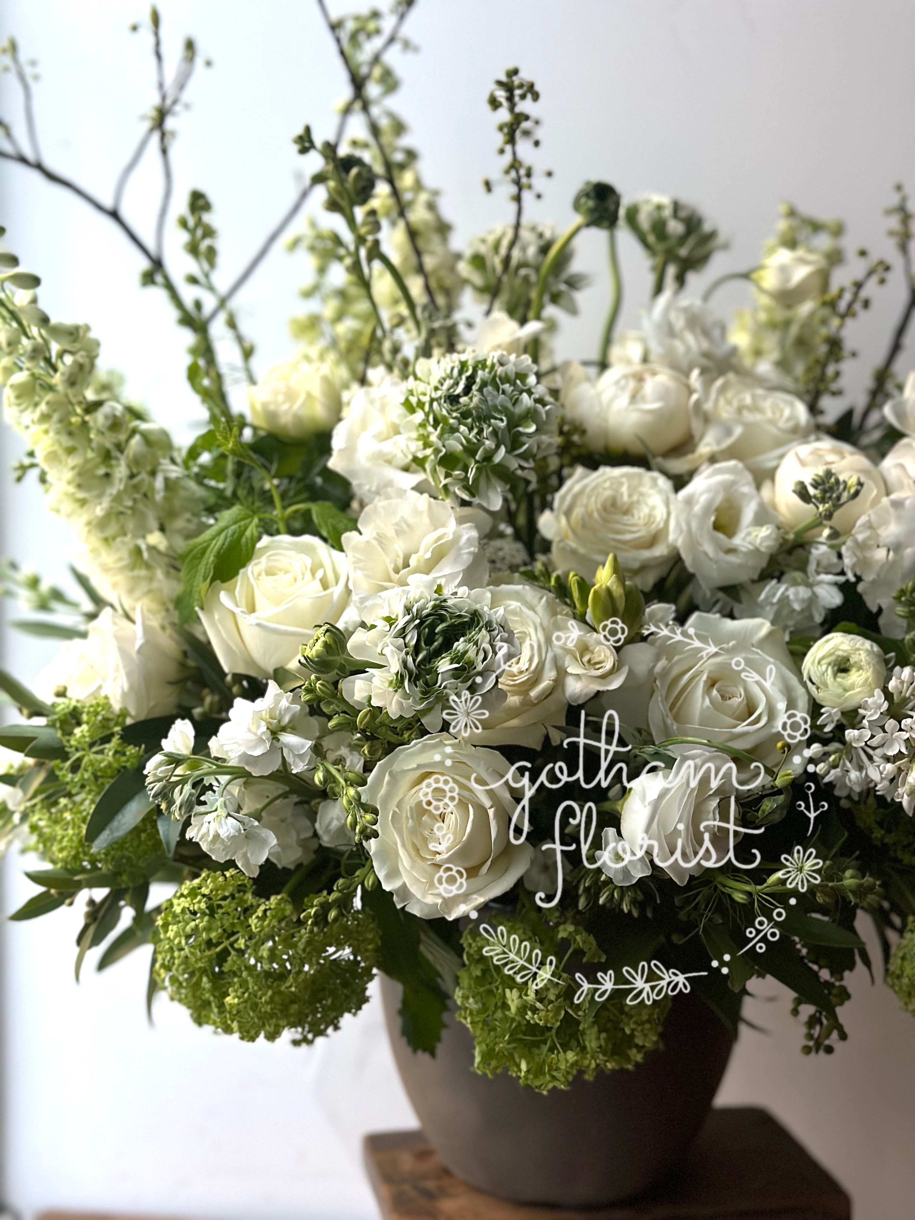 White roses and ranunculus arranged in a dark vase