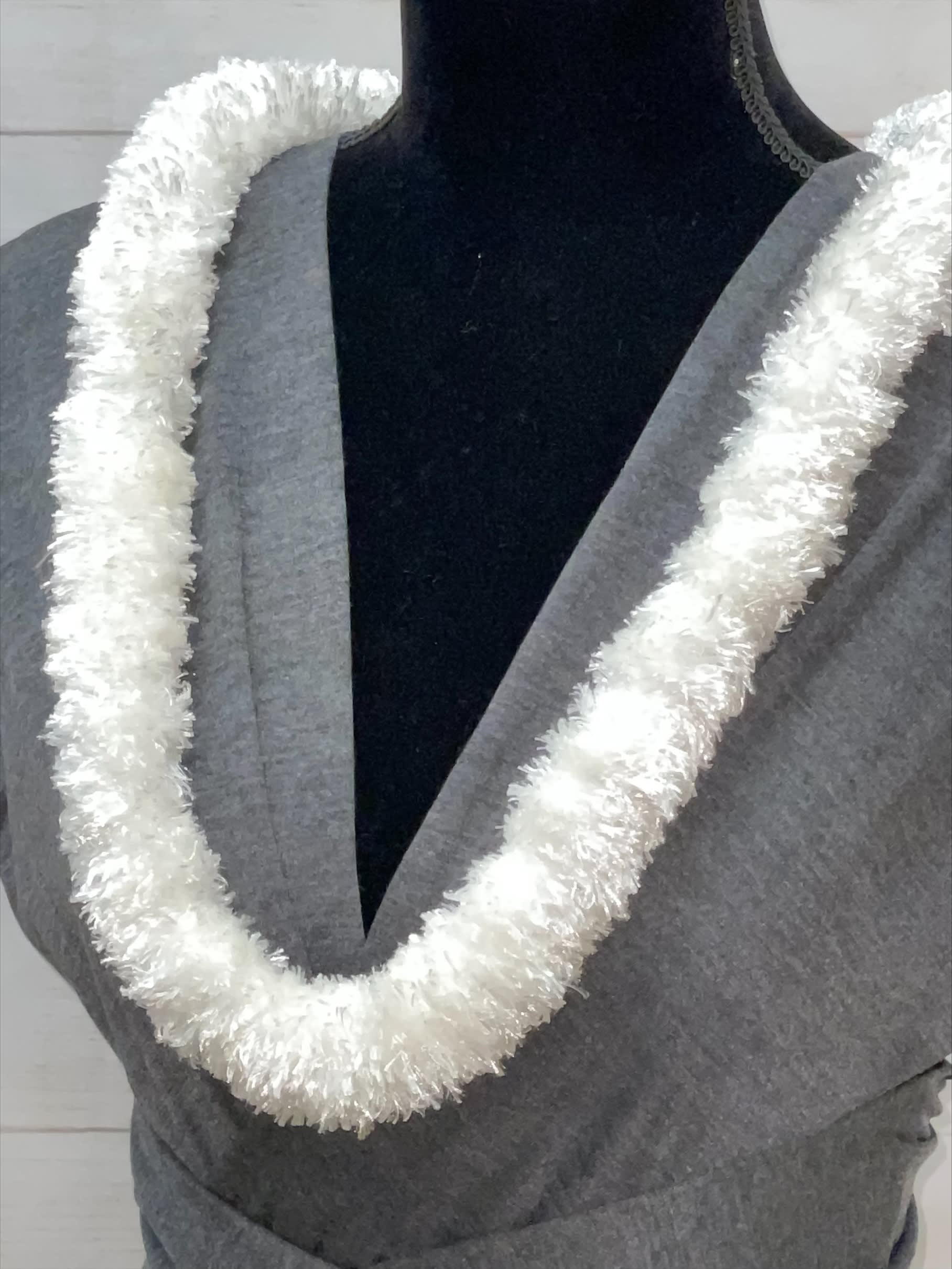 White fluffy lei-style garland displayed on a gray dress form