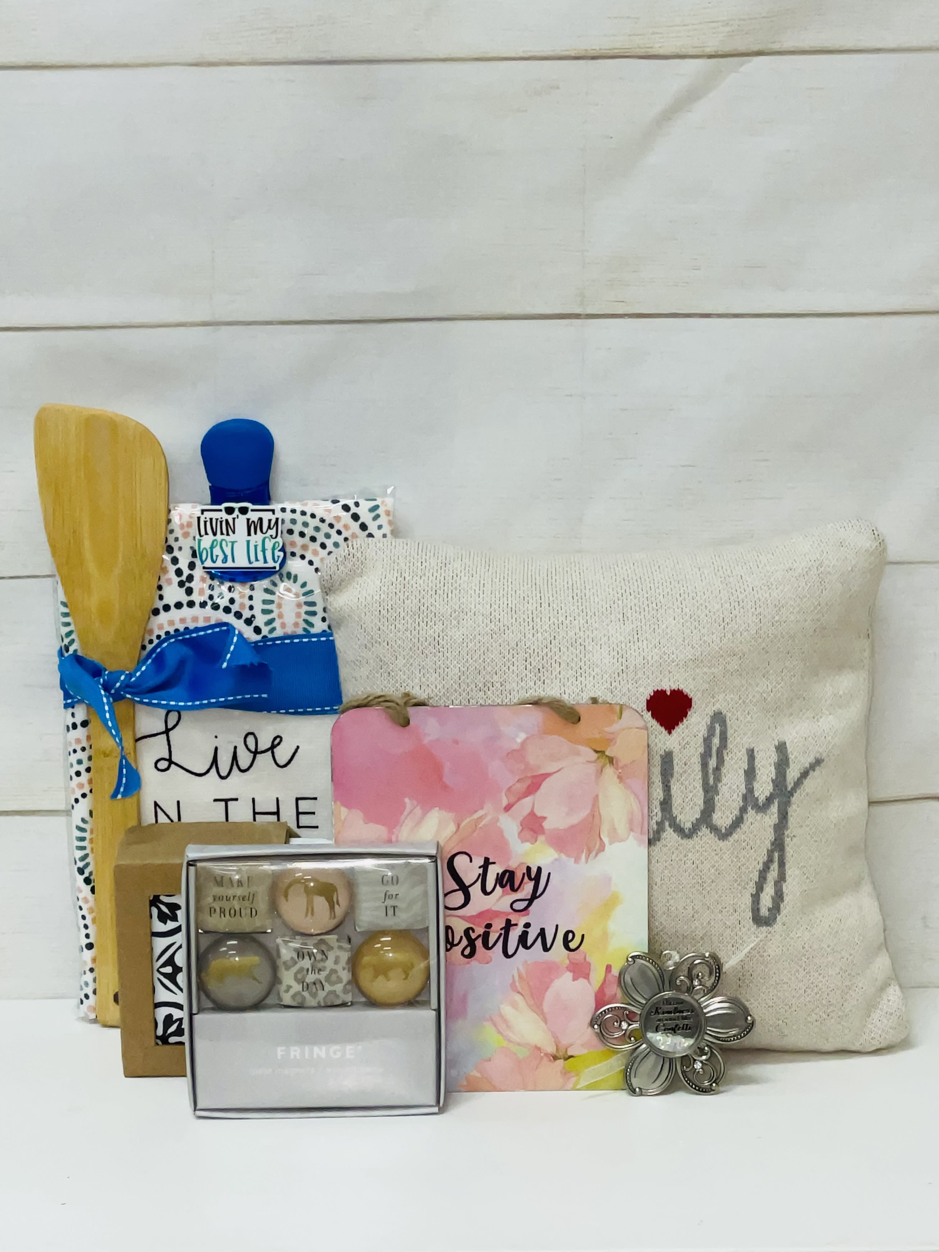 Gift set with pillow, kitchen utensils, positive message signs, and small boxed accessories.