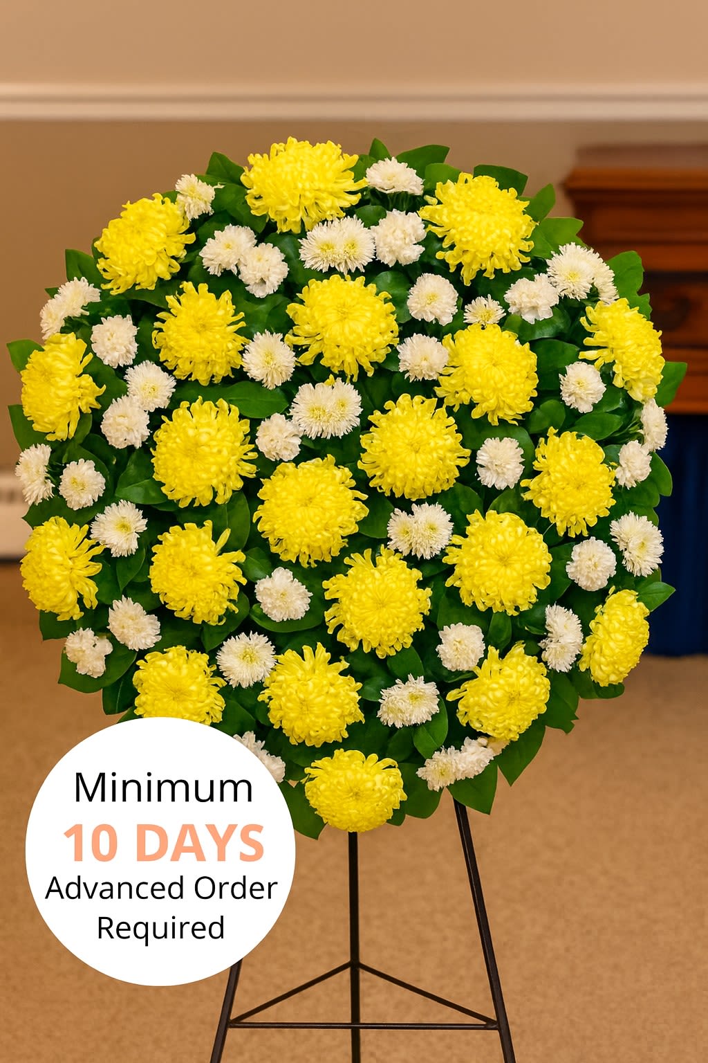 Round standing spray of yellow and white chrysanthemums on a metal easel