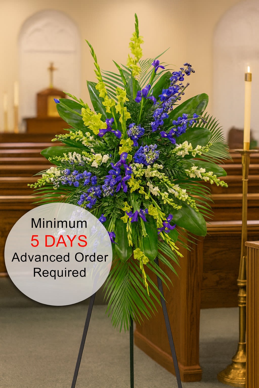 Tall standing spray of blue and yellow flowers with lush foliage on an easel in a church.