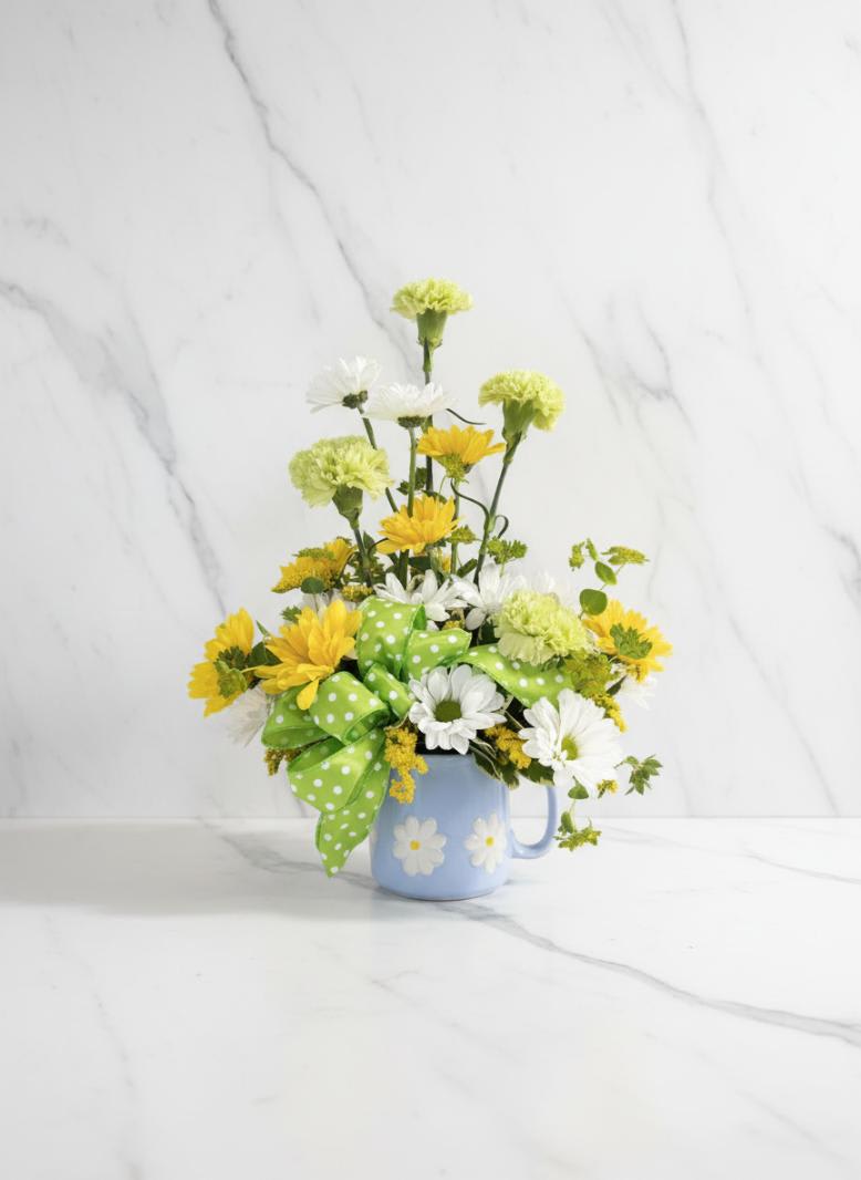 Yellow and white daisy bouquet in a blue mug with a green polka-dot bow