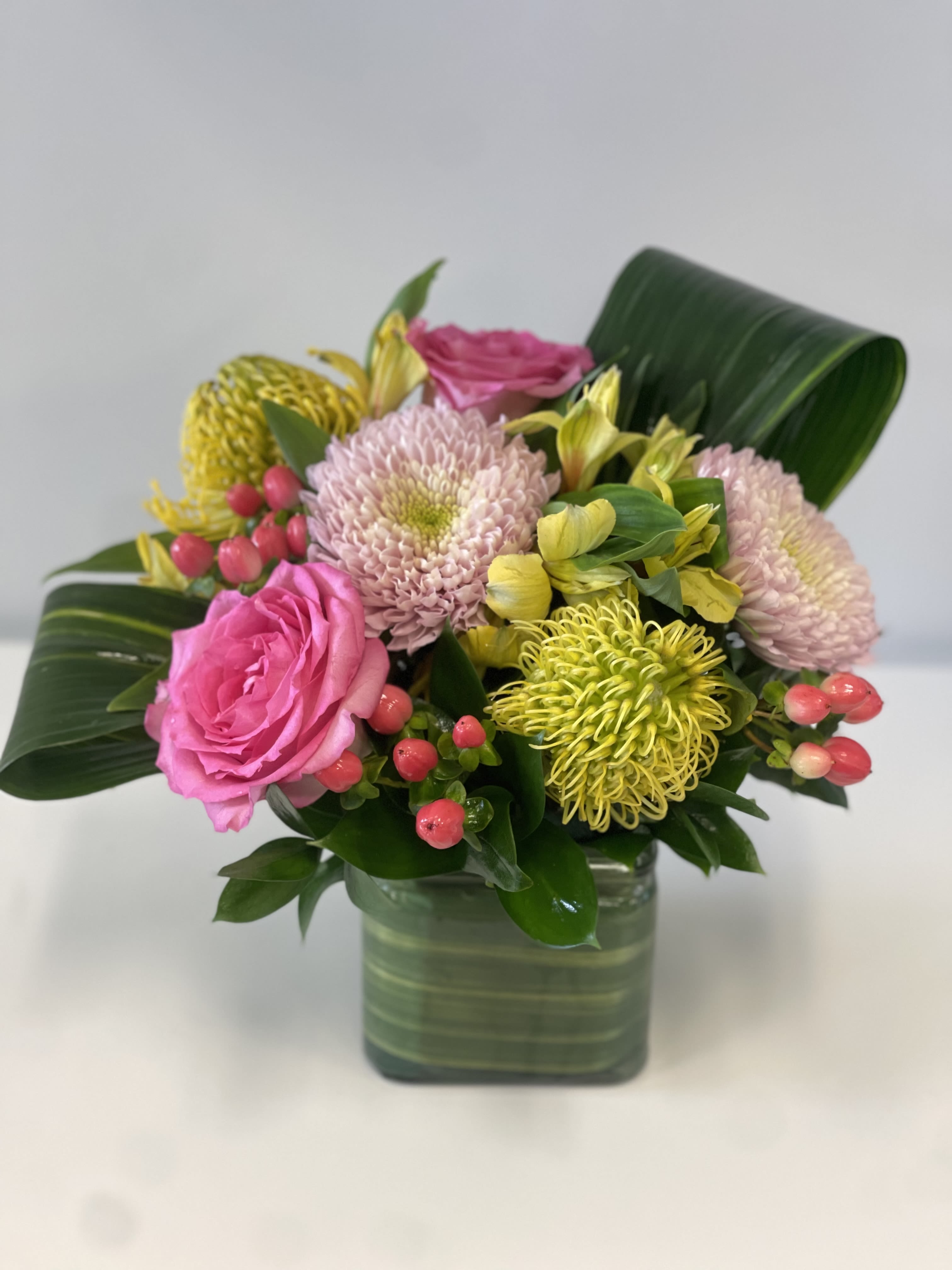 Pink roses and chrysanthemums in a square glass vase