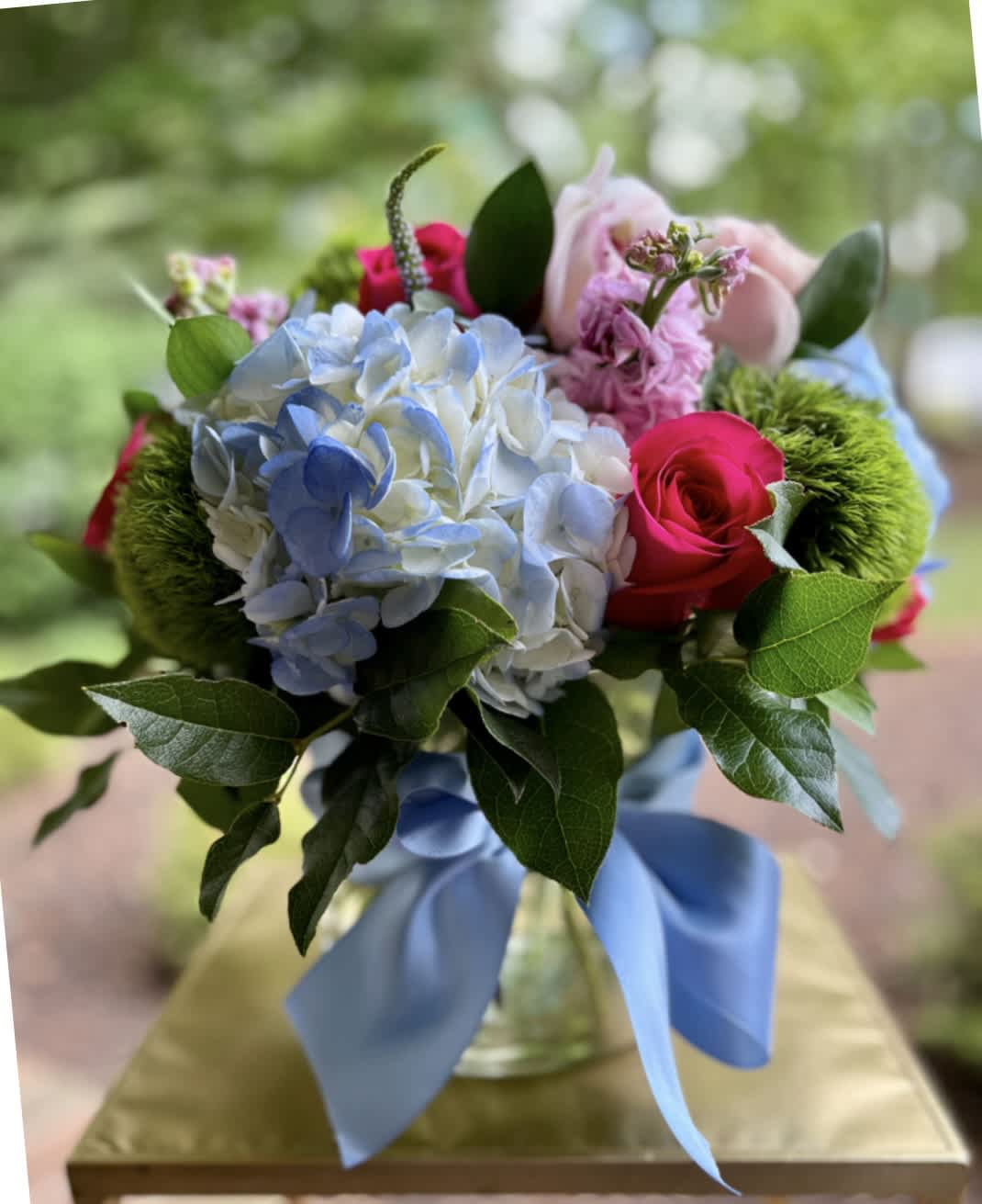Summer Dreams - Sweet Summer – Vibrant Blue &amp; Pink Floral Arrangement | Wilmington, Delaware Local Florist  Celebrate the delicate beauty of blue hydrangea and pink roses with Sweet Symphony, a fresh and vibrant floral arrangement handcrafted by your trusted Wilmington, Delaware florist. This stunning bouquet features lush blue hydrangea, bold hot pink roses, delicate light pink lisianthus, and textured green trichilium. Beautifully arranged in a clear glass cylinder vase and tied with a soft light blue ribbon, this design brings a refreshing pop of color to any occasion.  Perfect for birthdays, anniversaries, summer celebrations, or simply to brighten a loved one’s day. Available for same-day flower delivery in Wilmington, DE and nearby communities. Trust our local flower shop for fresh, premium blooms and exceptional service.