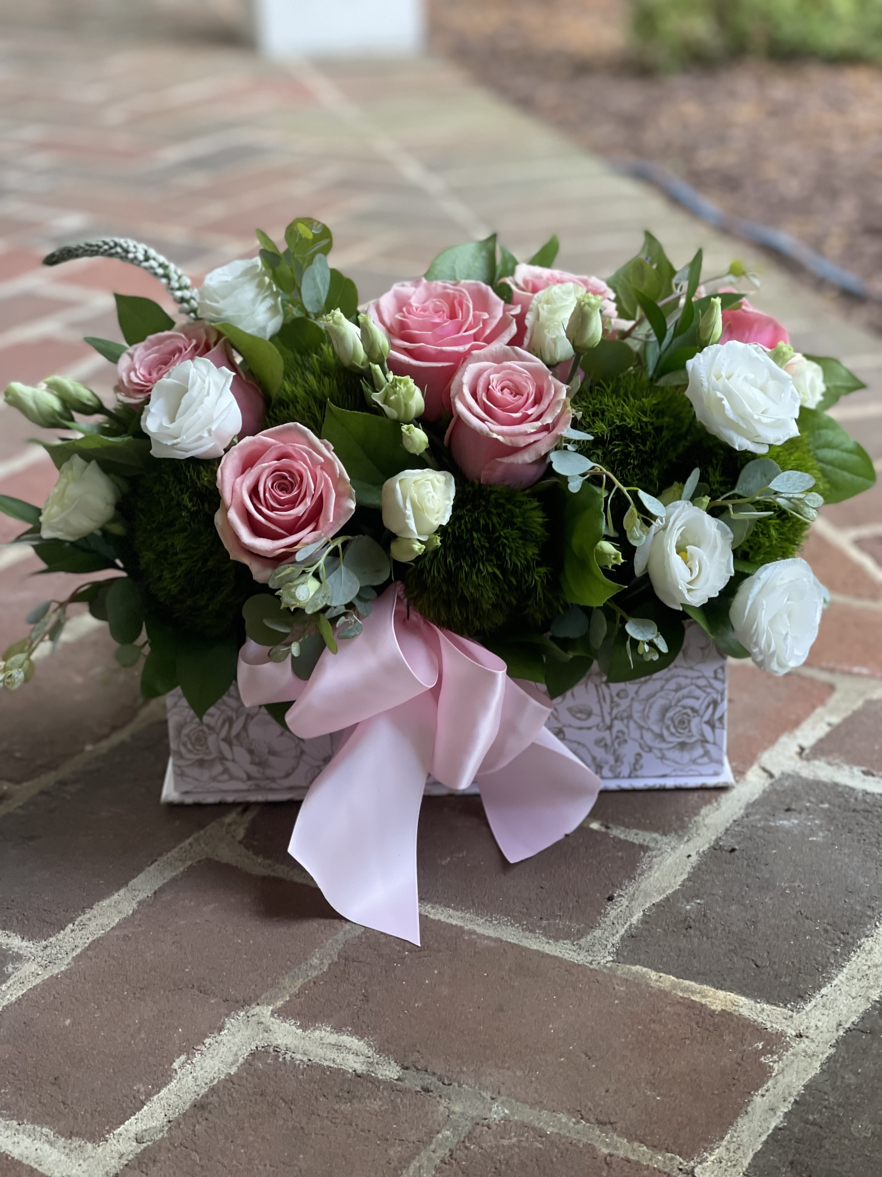 Pink and white roses in a decorative box with a pink ribbon