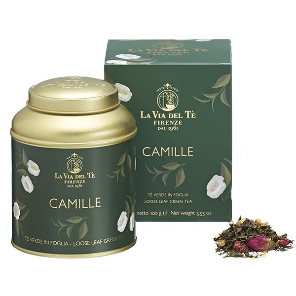 Green tea tin and box with floral accents beside loose tea leaves