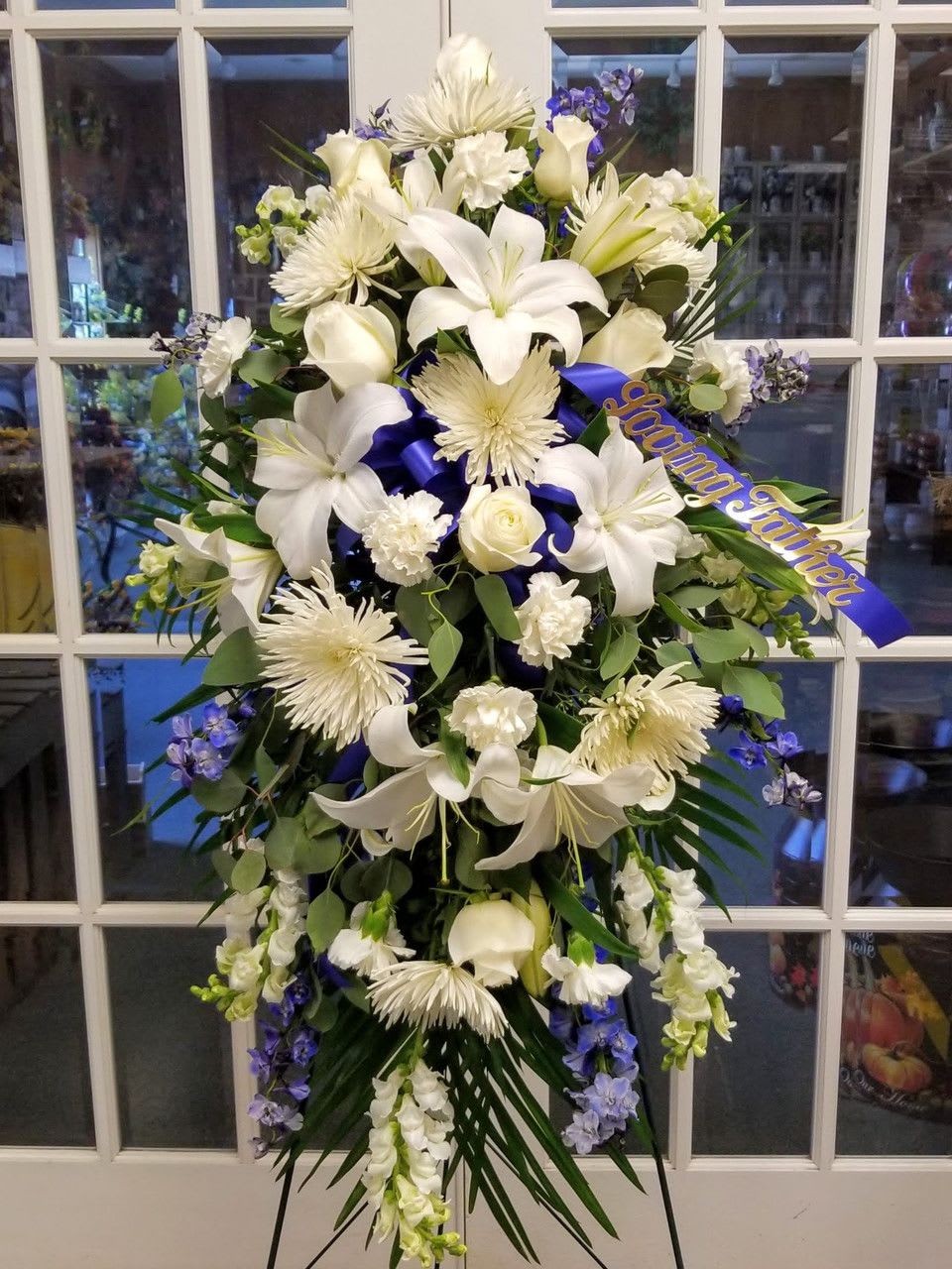 White funeral spray with lilies, roses, and chrysanthemums on a stand