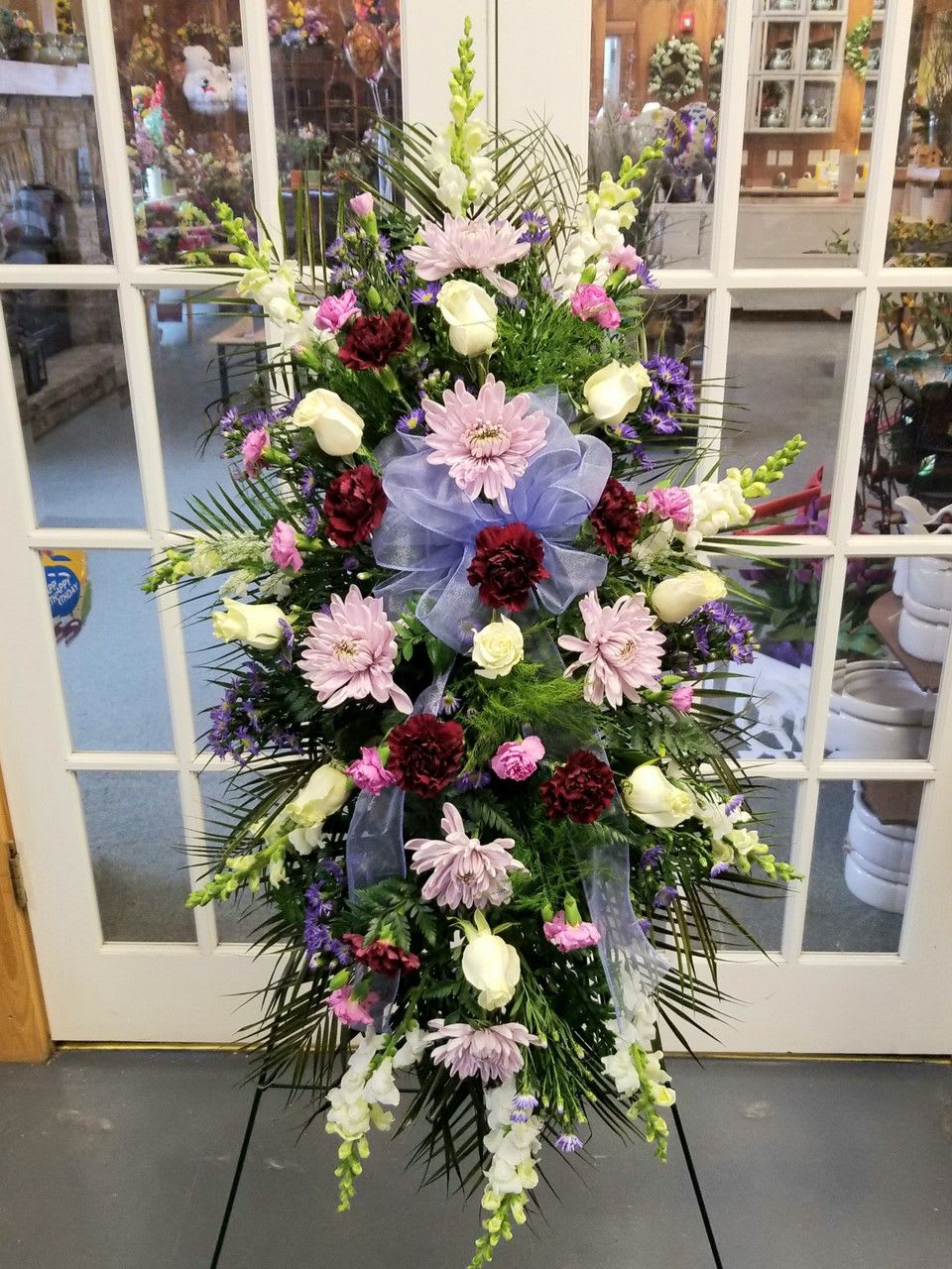 Standing floral spray with pink, white, and purple flowers on an easel