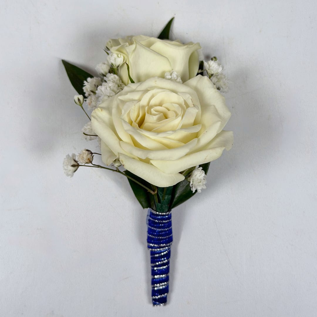Sapphire Boutonniere - With Wrap - Two cream-white roses, clustered tightly with delicate white filler blooms and dark green leaves, create a quietly elegant boutonniere perfect for prom or other dressy occasions. The cool royal-blue and silver stem wrap gives this boutonniere a striking, refined accent, ideal for anyone who should stand out with subtle sophistication.  This version of the design is in the shimmering blue and silver ribbon pictured, and a boutonniere pin is included so it sits neatly on a suit or jacket. If you want to change the color of either the ribbon wrap or add dazzling sparkle accents to your boutonniere, check out our add-ons and pick your desired color.