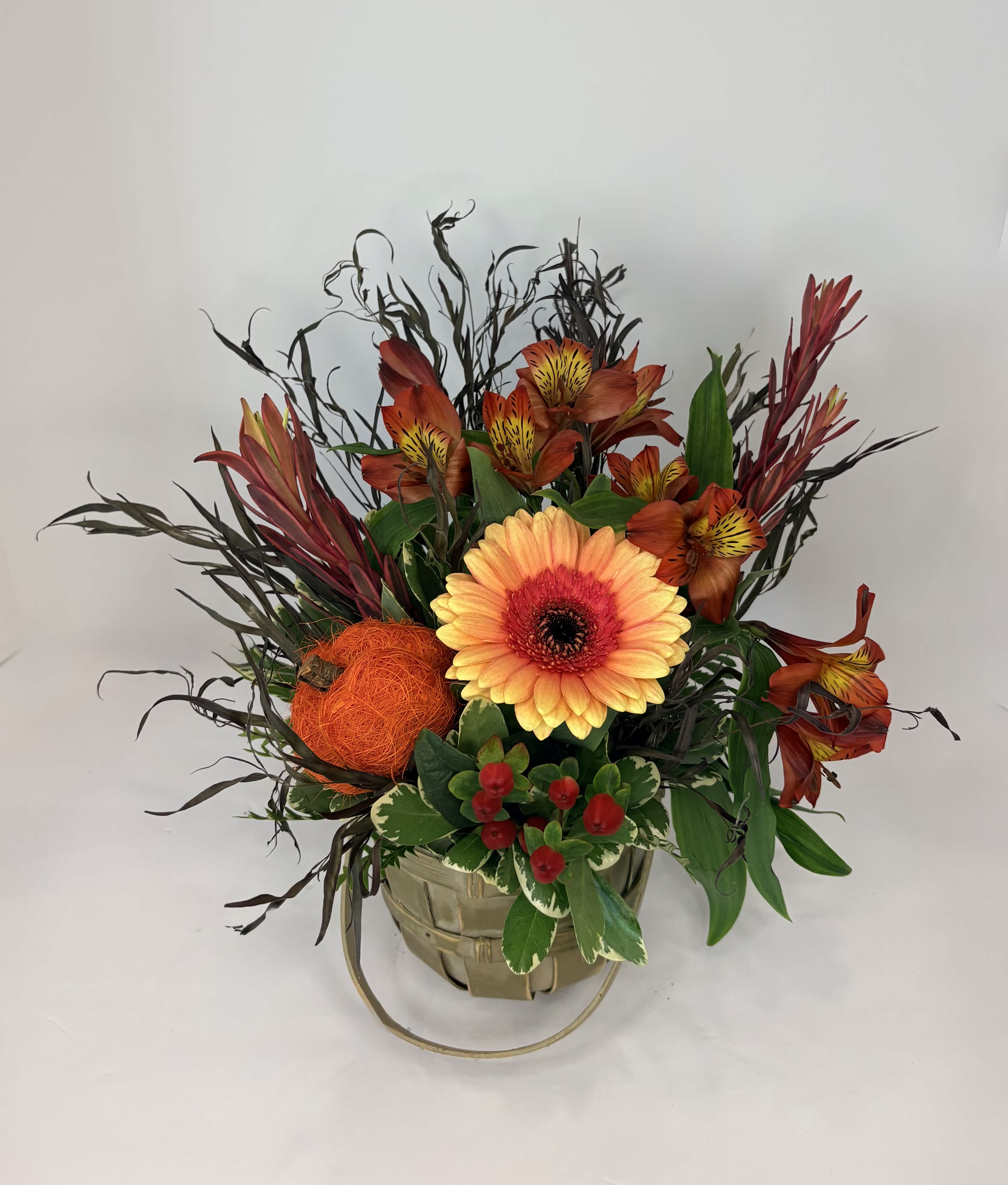 Orange and red floral arrangement in a basket with a large gerbera daisy