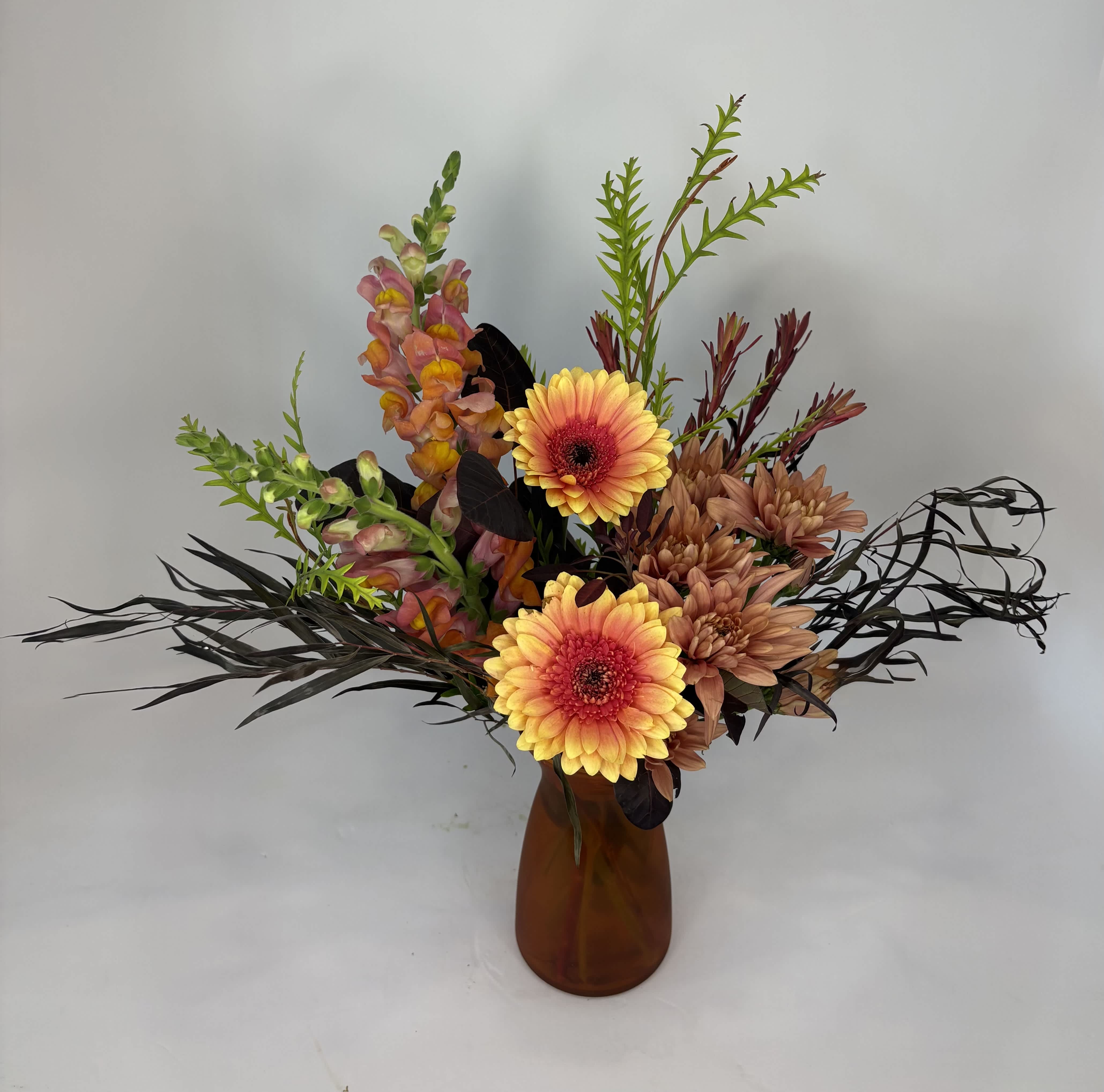Mixed bouquet with yellow gerbera daisies and peach flowers in an amber vase