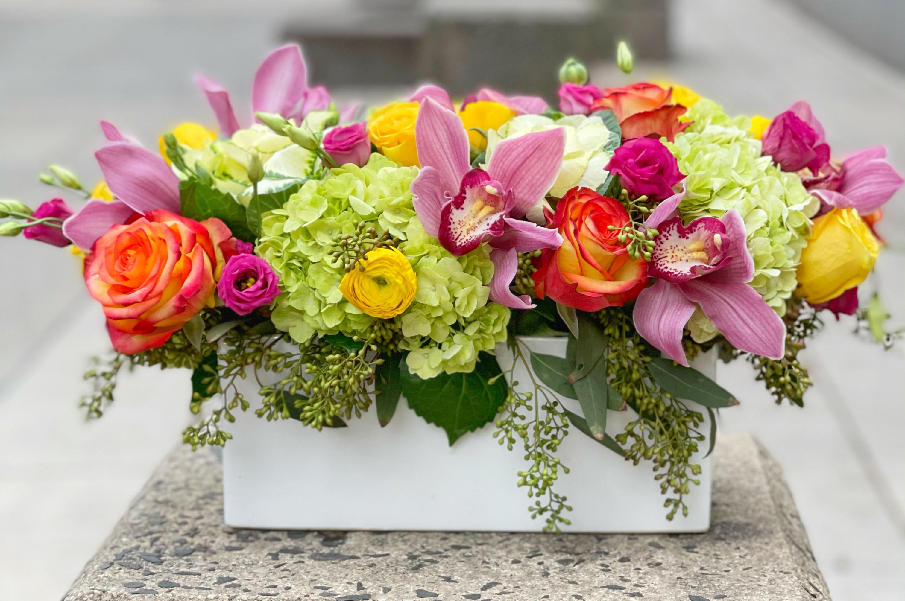 Colorful floral arrangement in a white rectangular vase