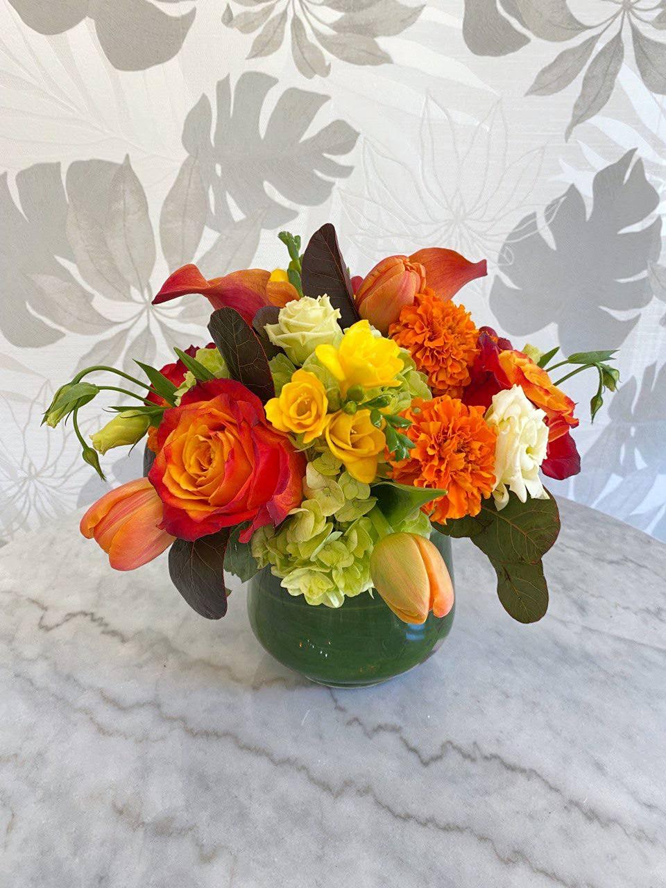 Colorful bouquet of roses, tulips, and hydrangeas in a green vase