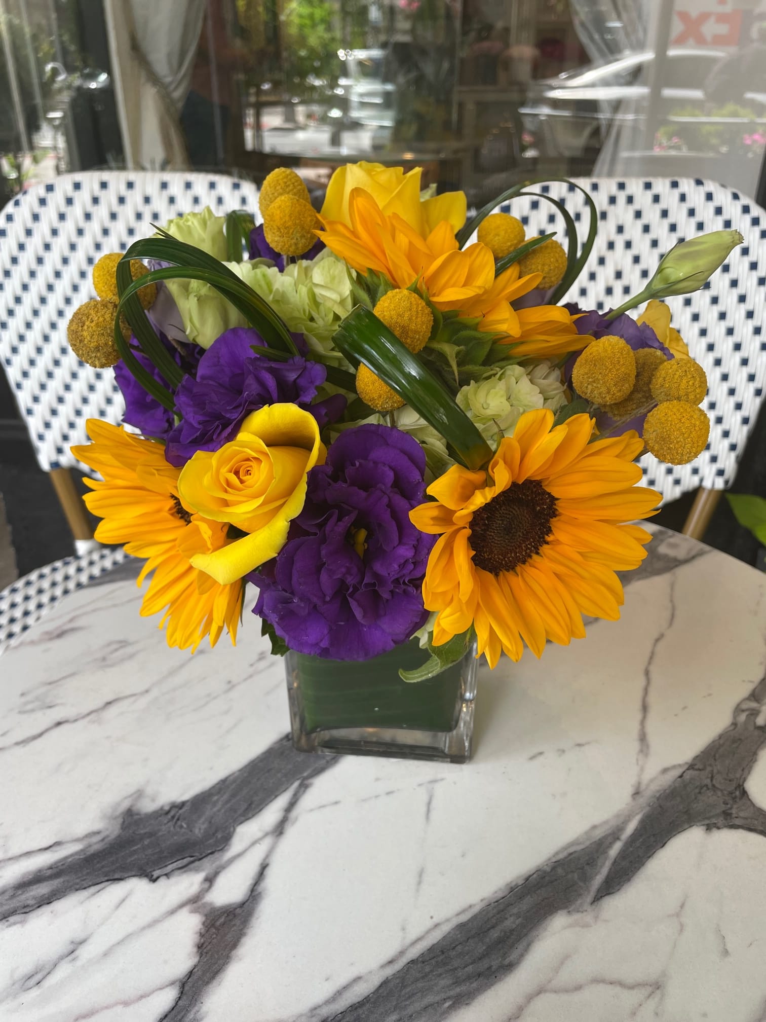 Bouquet of yellow and purple flowers in a clear glass vase