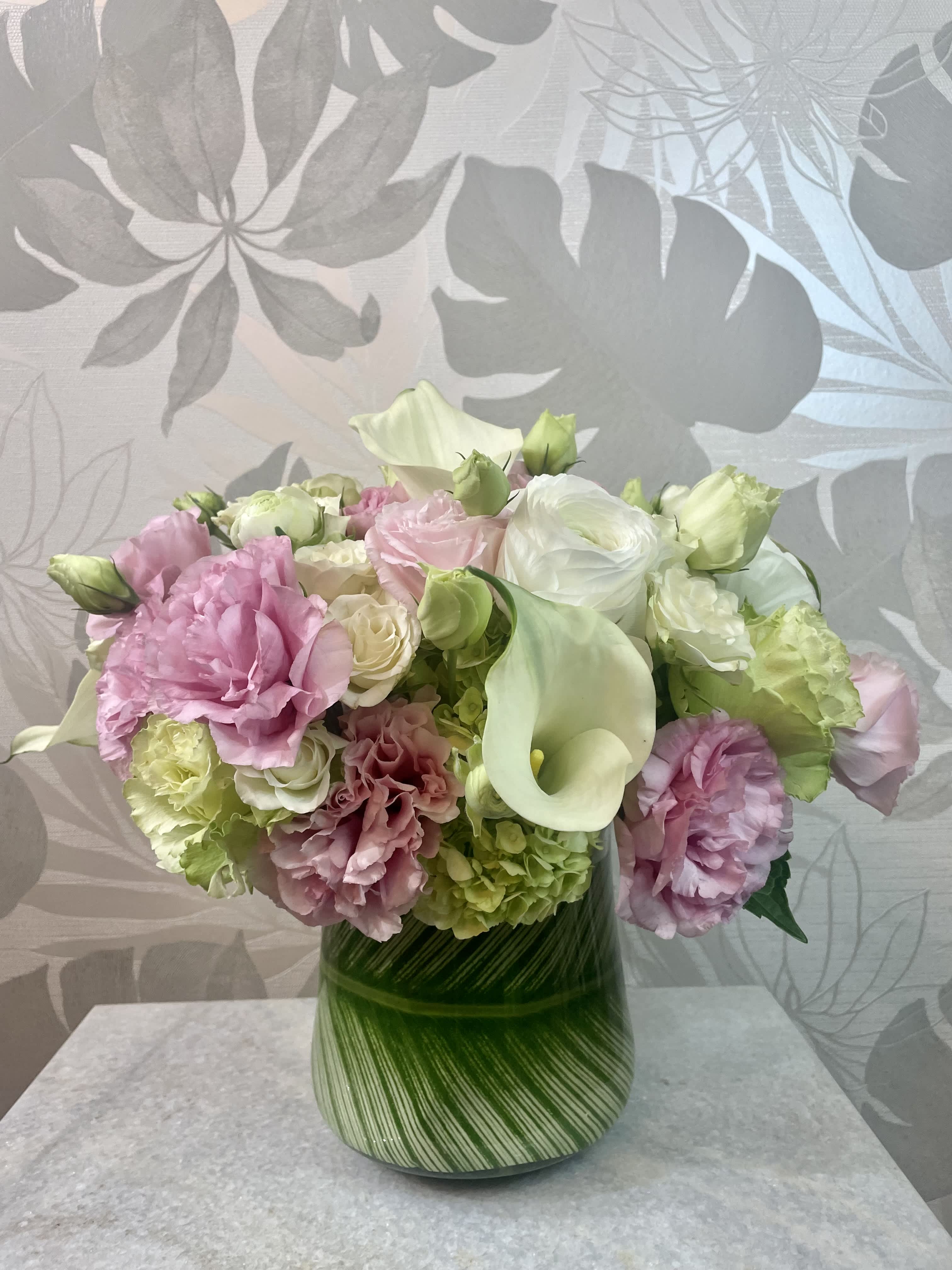 Pink and white flowers arranged in a green striped vase