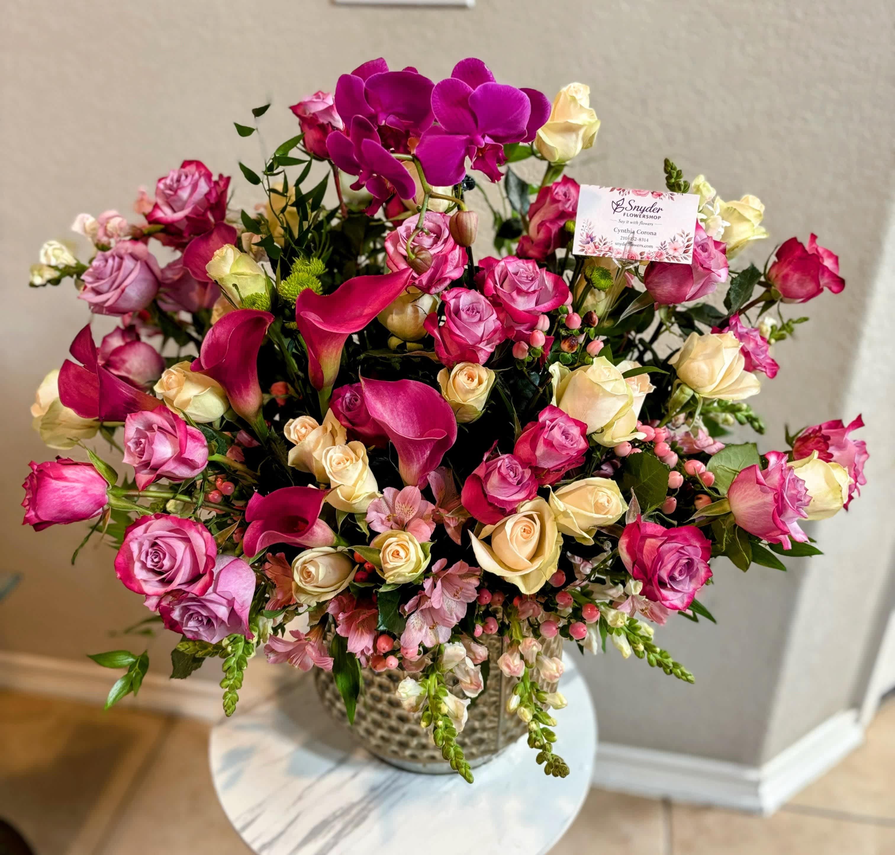 Pink and cream roses with magenta orchids in a vase