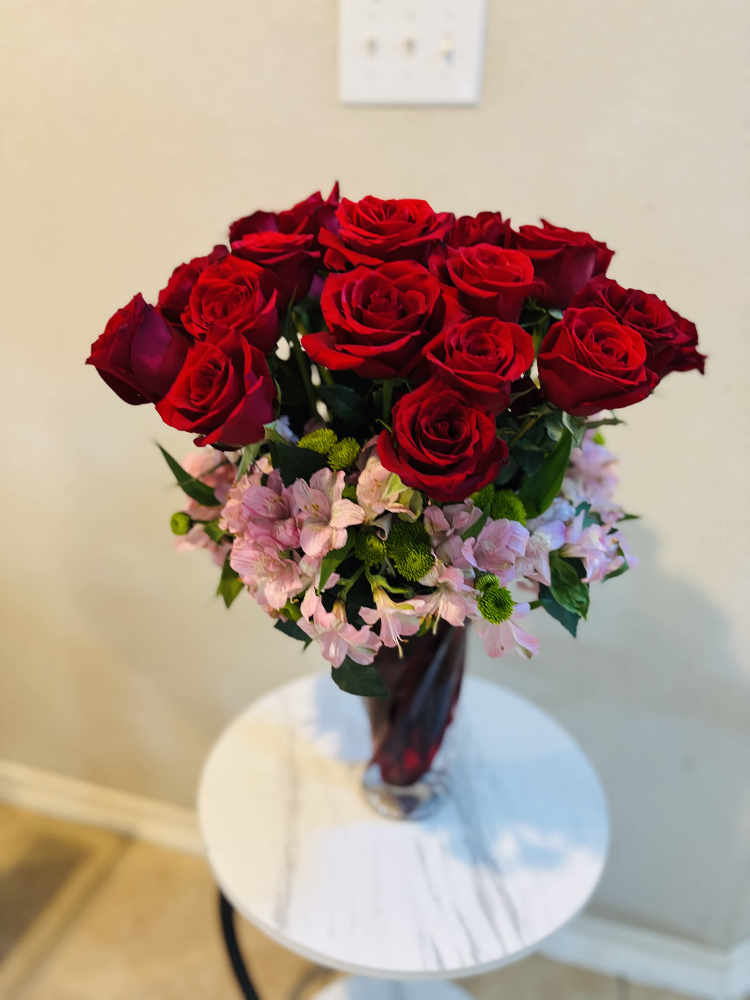 Bouquet of red roses with pink filler flowers in a glass vase