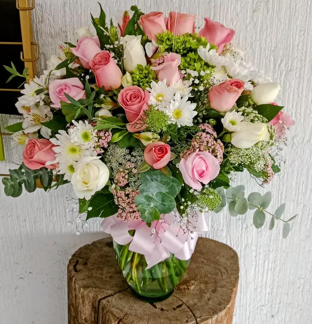 Pink and white rose bouquet in a glass vase with a ribbon
