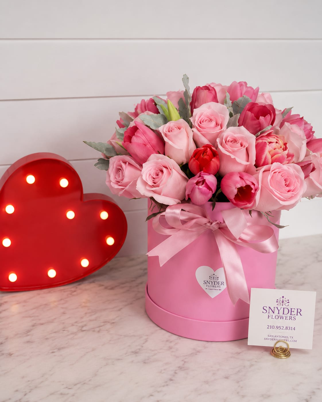 Pink roses and tulips in a pink hat box with a ribbon
