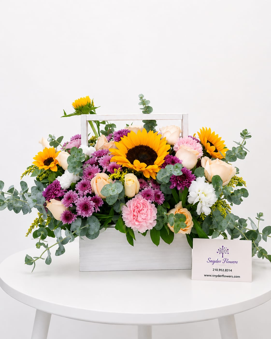 Mixed bouquet in a white wooden box with sunflowers, roses, and purple blooms