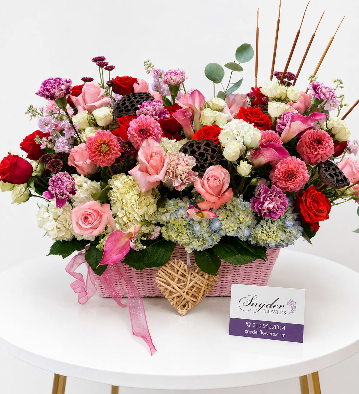Pink and red mixed flower arrangement in a pink basket with ribbon