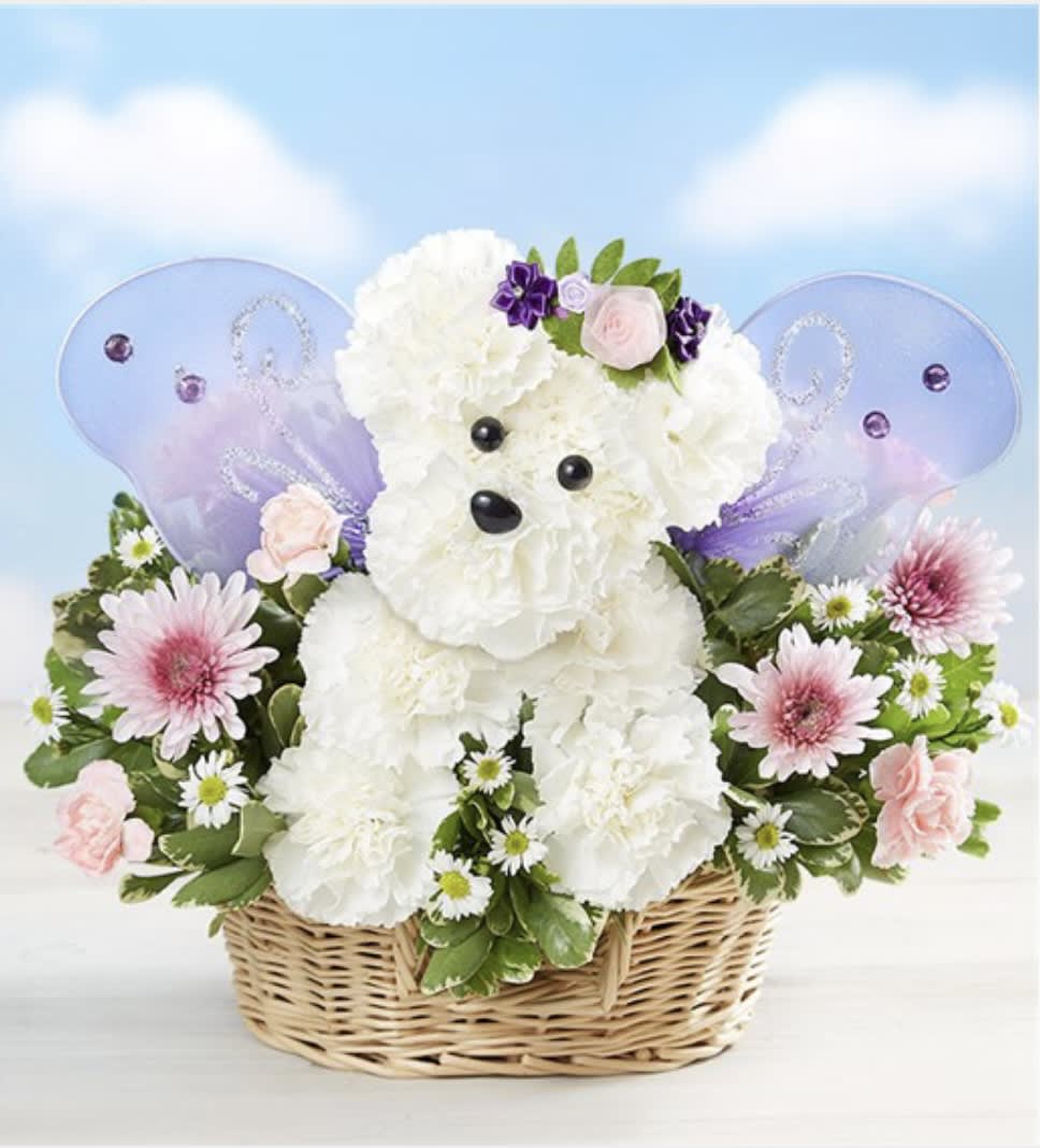 White teddy bear in a wicker basket surrounded by pink and purple flowers