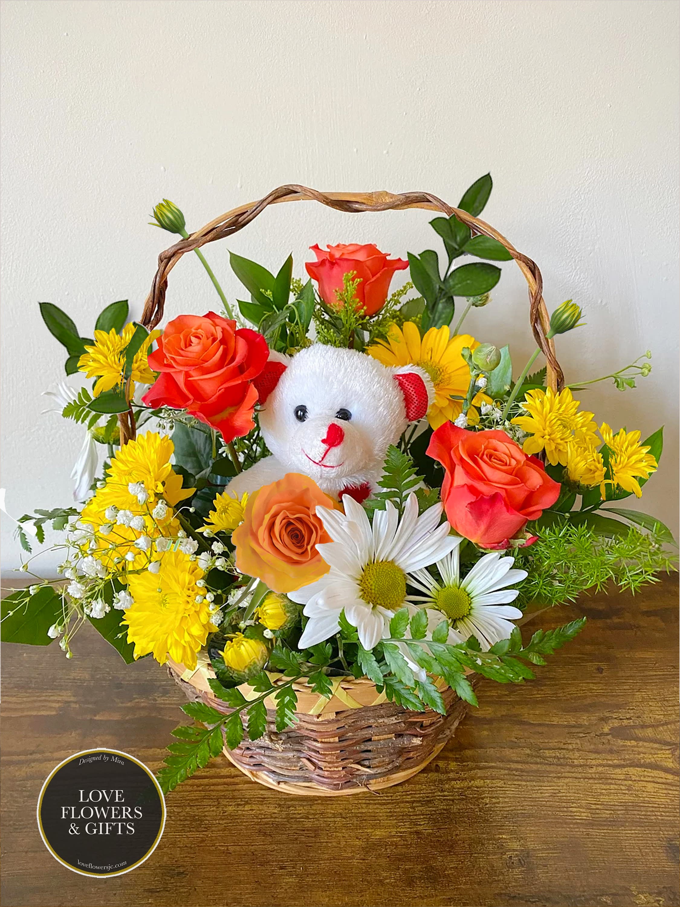 Basket arrangement of orange roses and yellow and white daisies with a small white teddy bear in the center