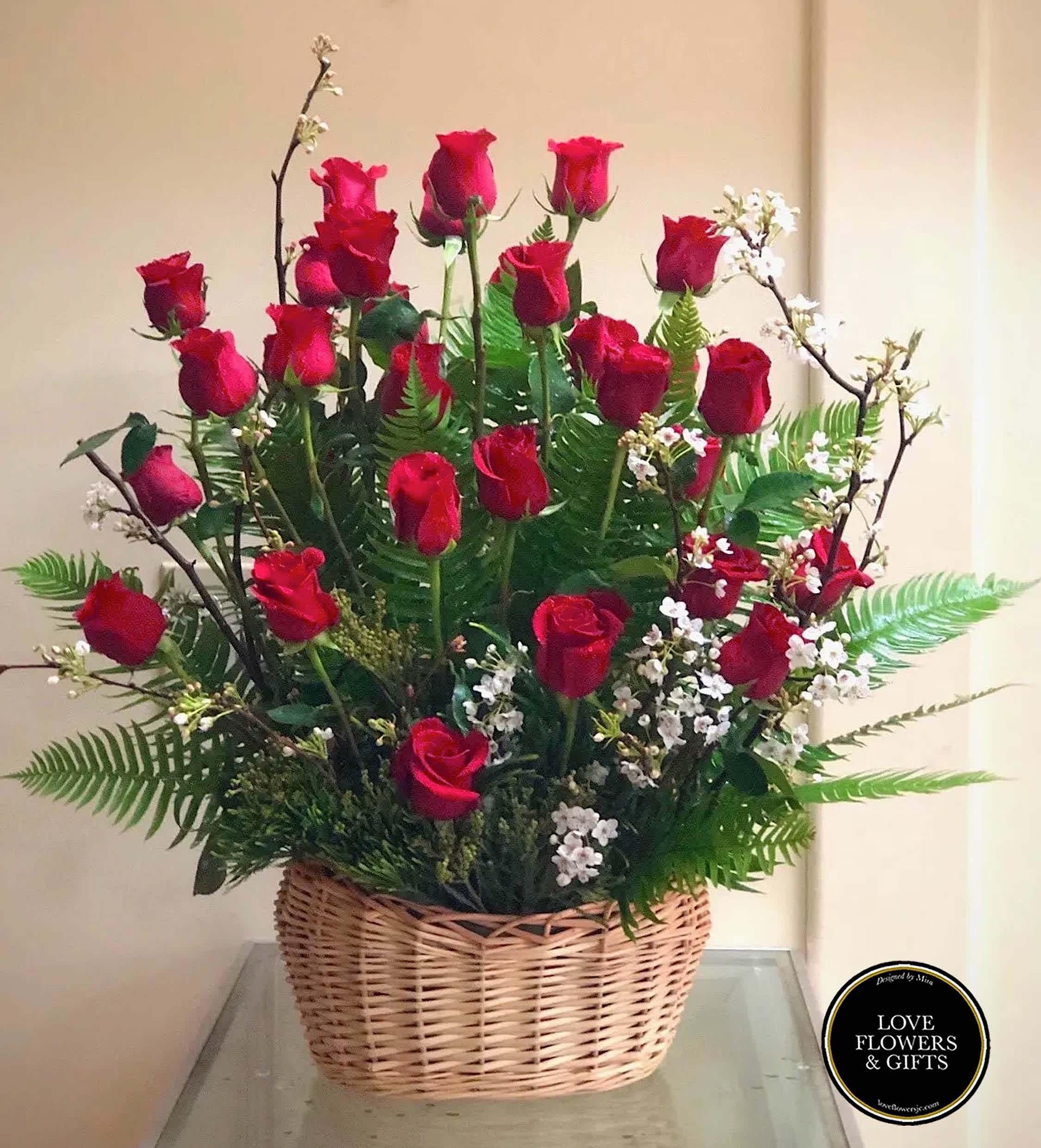 Basket arrangement of tall red roses with white filler flowers and ferns.