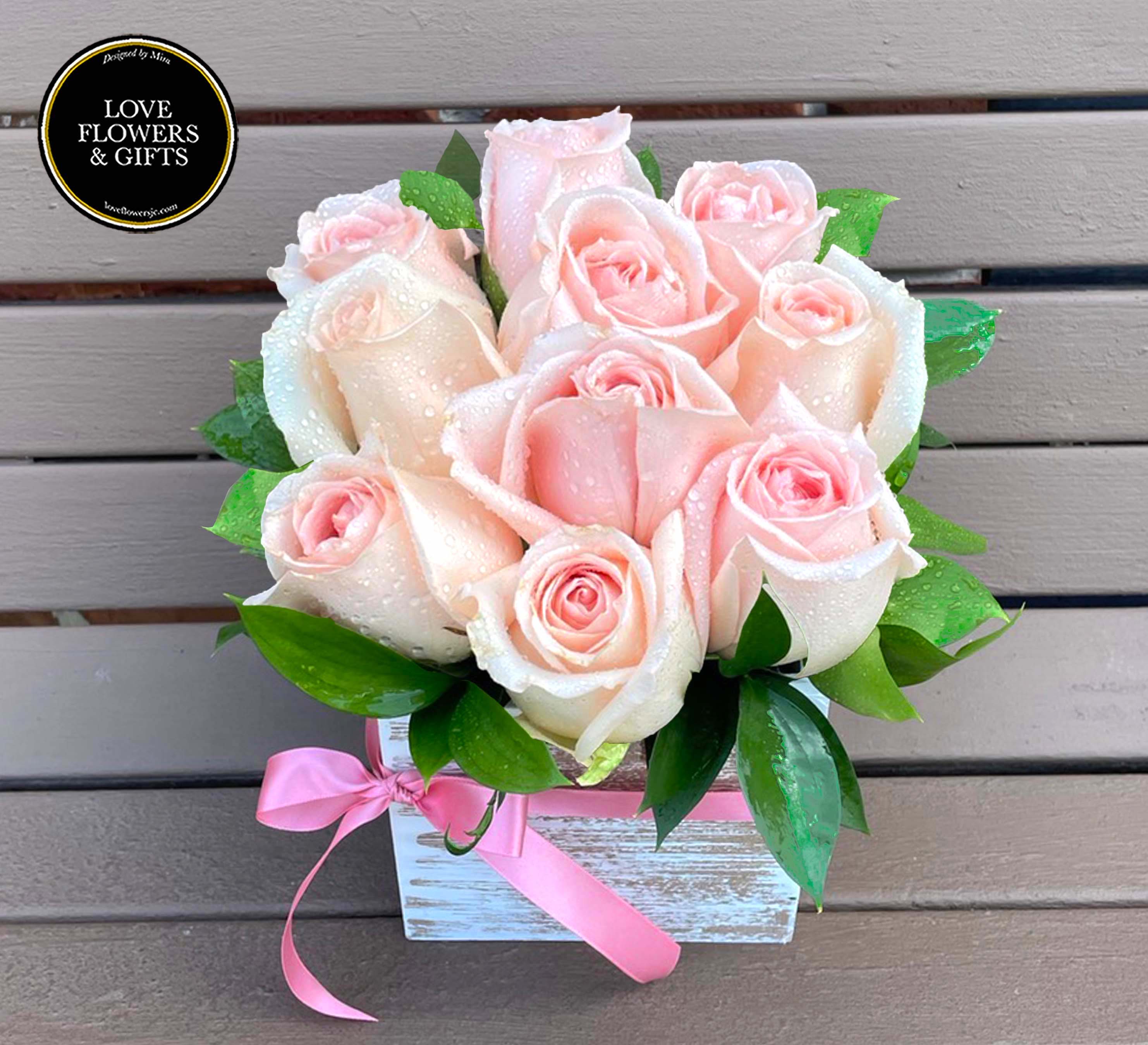 Blush pink roses with water droplets in a white wooden box tied with a pink ribbon