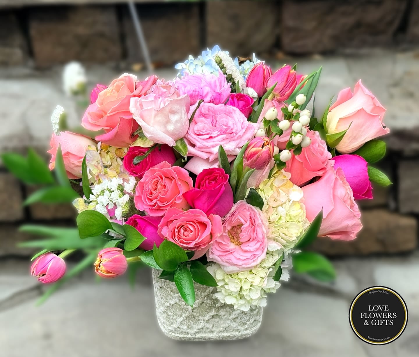 Garden Roses Pink - Designed in a elegant stone vase with garden roses and various blooms in pinks and corals. 