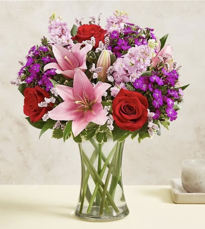 Pink lilies and red roses in a clear glass vase