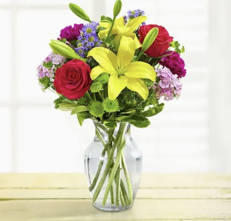 Bouquet of red roses and yellow lilies in a clear glass vase
