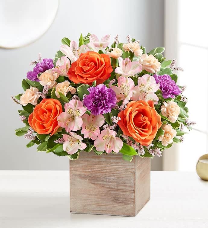Bouquet of orange roses, pink alstroemeria, and purple carnations in a wooden box