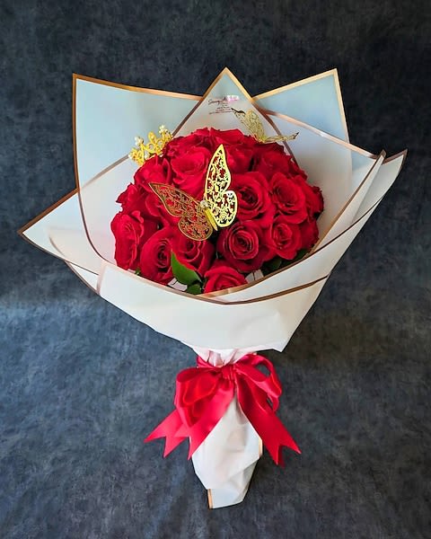Bouquet of red roses wrapped in white paper with a red ribbon
