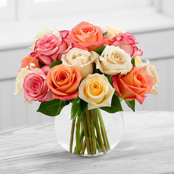 Bouquet of pink, peach, and cream roses in a clear glass vase
