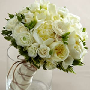 White rose bouquet in a clear glass vase with a brown ribbon