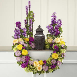 Floral wreath with yellow and lavender roses around a dark urn