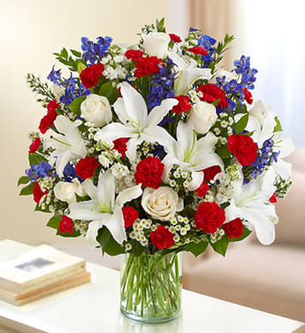 Sincerest Sorrow - Red, White and Blue - Product ID: 95444   Convey your deepest condolences for a beloved veteran with this touching tribute arrangement. A beautiful bouquet of red, white and blue blooms such as roses, lilies, delphinium, stock and more sends peaceful memories to the home or service. Lush red, white and blue arrangement of roses, lilies, delphinium, stock, carnations, mini carnations and monte casino, accented with variegated pittosporum, salal and myrtle Hand-designed by our select florists in a classic glass cylinder vase; vase measures 8"H Can be sent to the home of friends of family members or to the service, to honor a lost military veteran Large arrangement measures approximately 24"H x 22"L Medium arrangement measures approximately 22"H x 20"L Small arrangement measures approximately 20"H x 18"L Our florists hand-design each arrangement, so colors, varieties, and container may vary due to local availability Lilies may arrive in bud form and will open to full beauty over the next 2-3 days