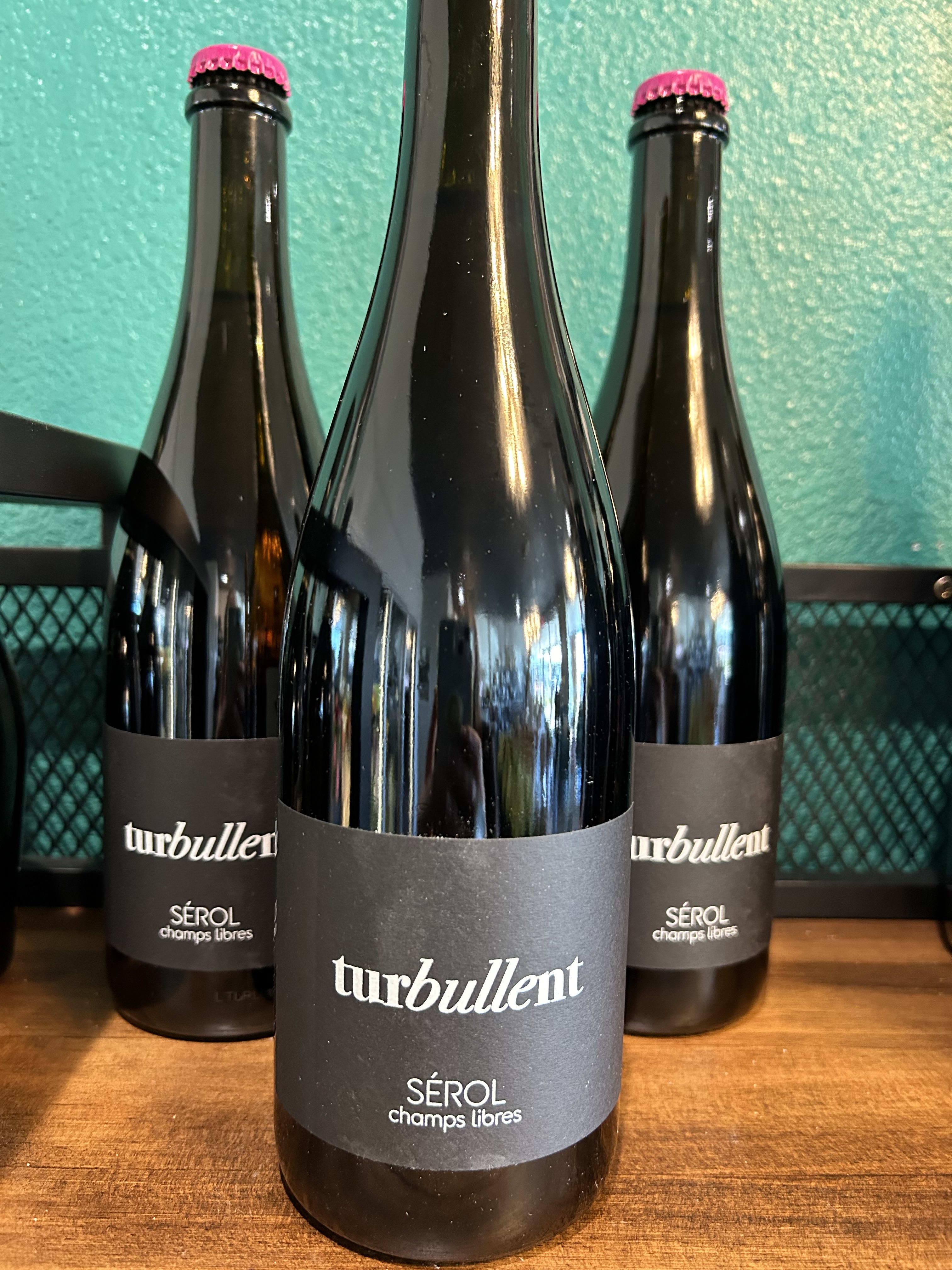Three dark wine bottles with black labels on a wooden surface