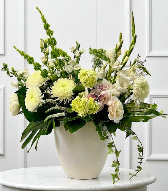 White floral arrangement in a cream vase with tall green stems