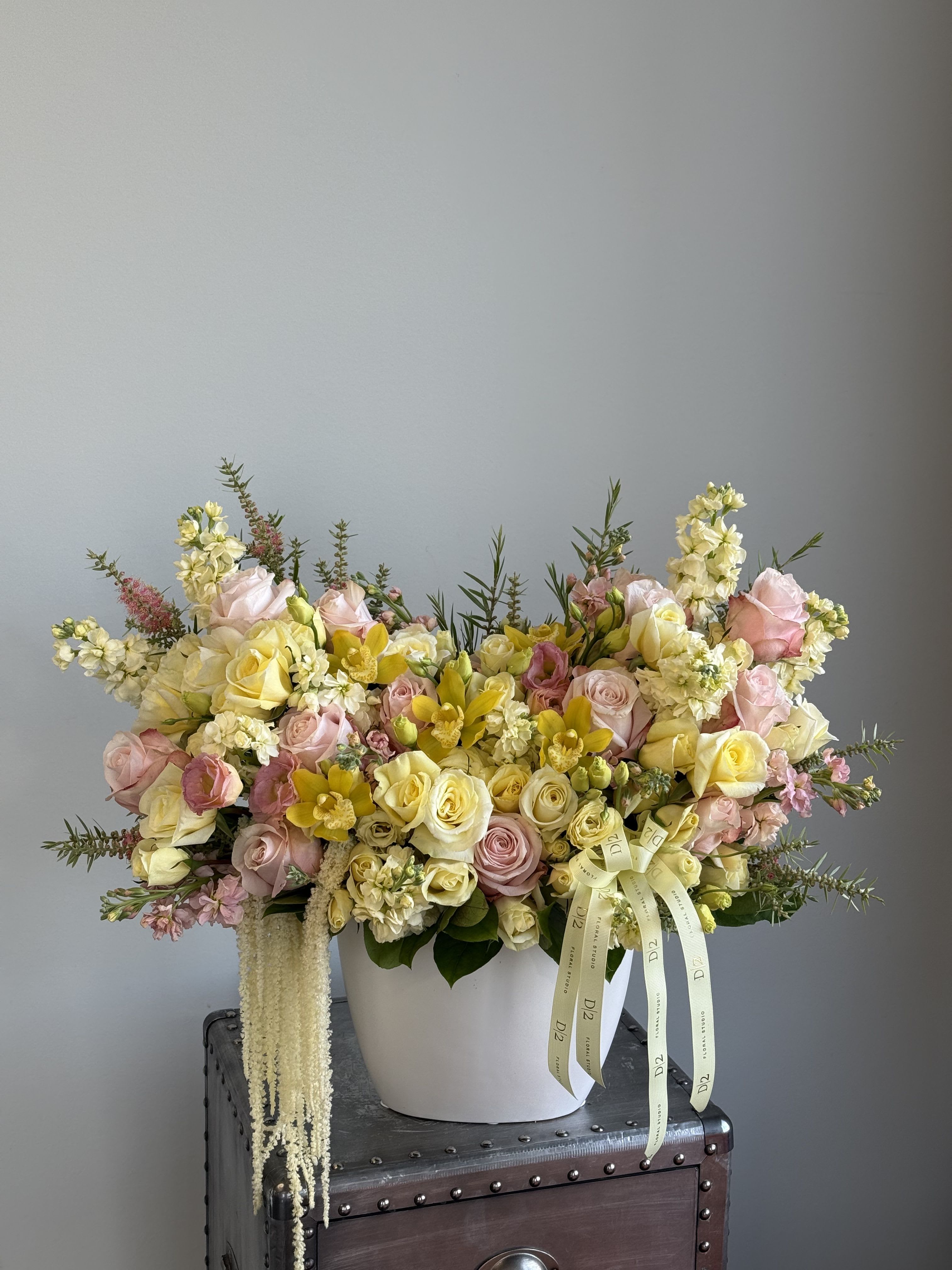 Large pastel flower arrangement in a white vase with pink and yellow blooms