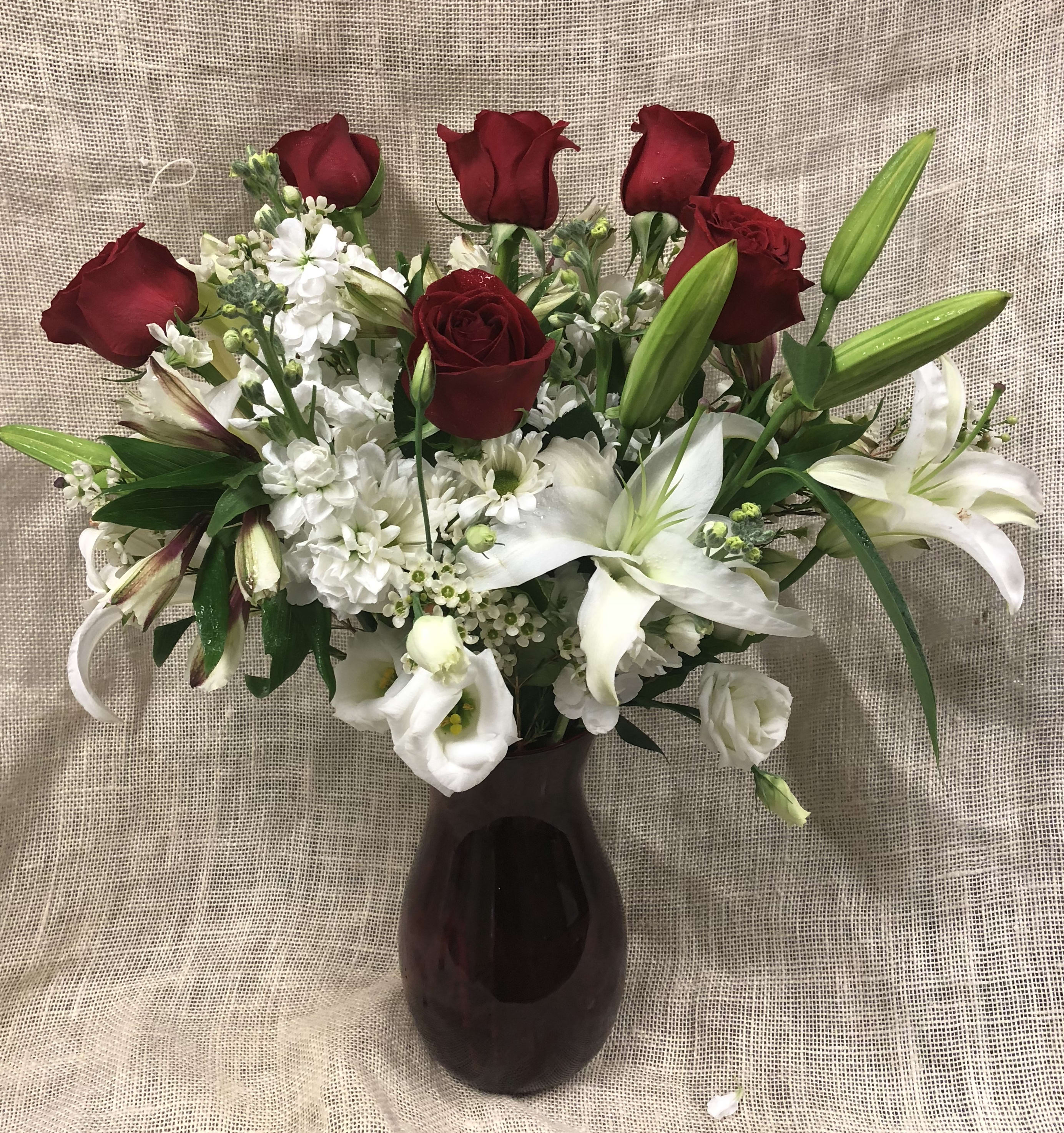 Red roses and white lilies arranged in a dark vase