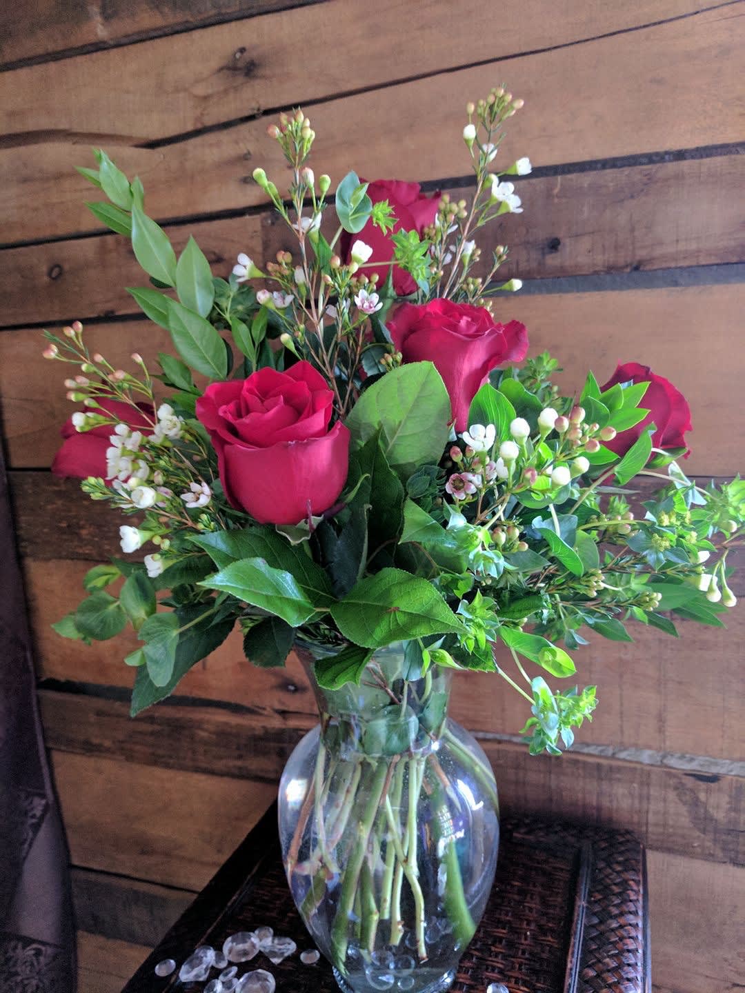 Bouquet of red roses and white filler flowers in a clear glass vase