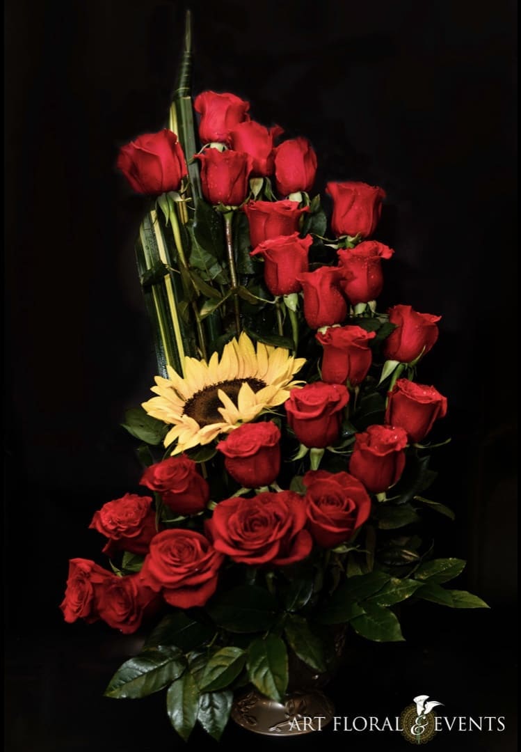 Tall bouquet of red roses with a yellow sunflower against a black background