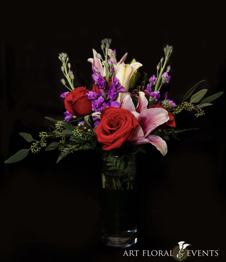 Red roses and pink lilies in a clear glass vase