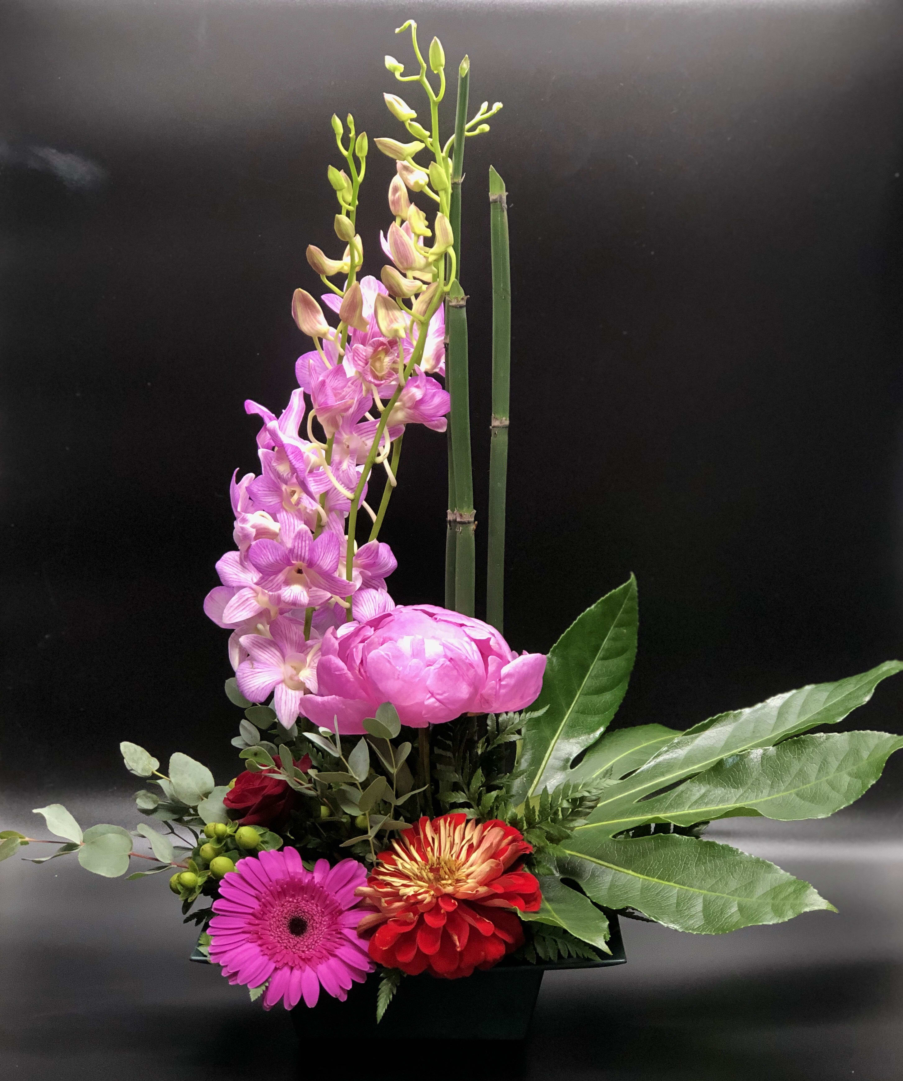 Pink orchids and mixed flowers arranged in a black container