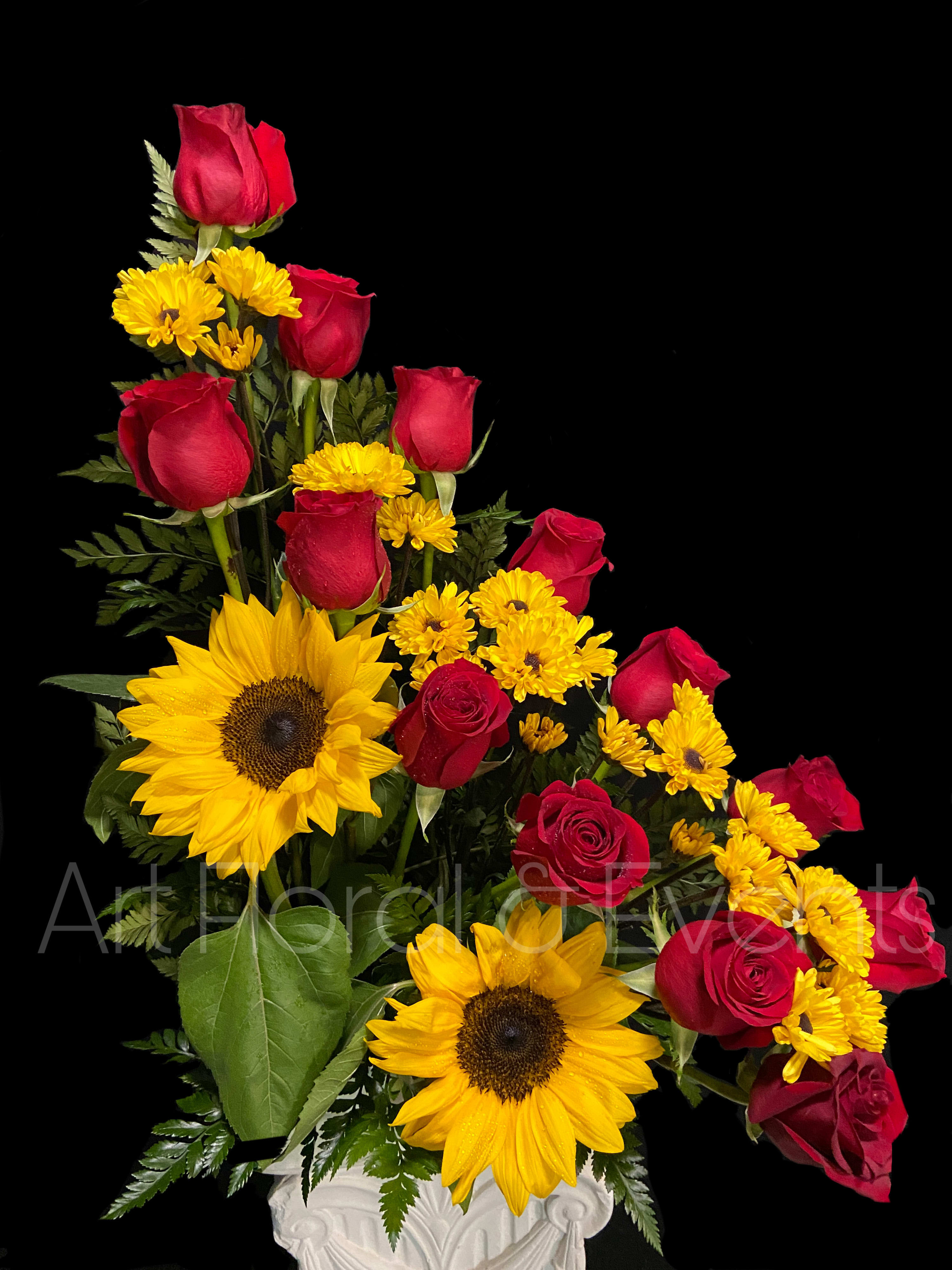 Red roses and yellow sunflowers in a white vase